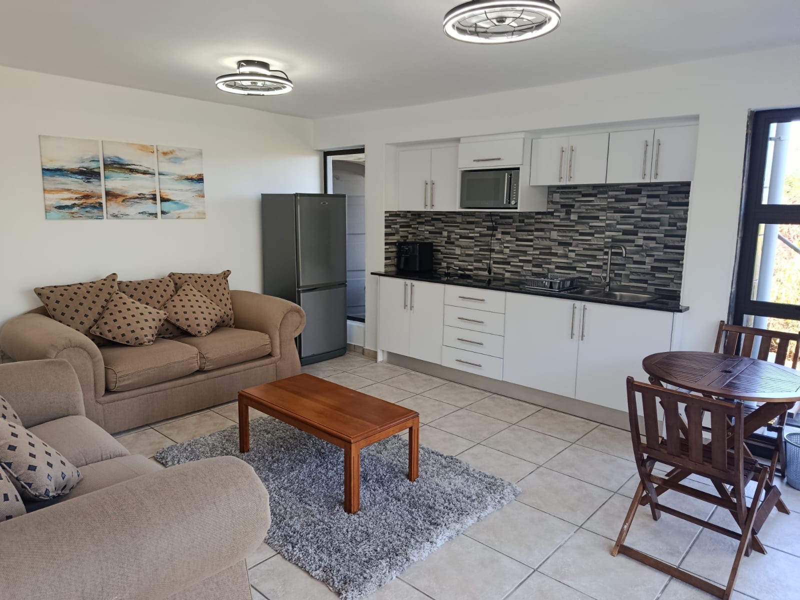 Open-plan lounge with two sofas and a fitted kitchenette